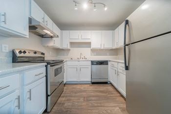 a white kitchen with stainless steel appliances and white cabinets